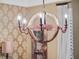 Detailed view of a rustic dining room chandelier with vintage bulbs, set against patterned wallpaper and wooden accents at 2750 Lee Shore Loop, Orlando, FL 32820