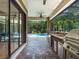 An outdoor kitchen with stainless steel appliances overlooks the pool in this screened-in backyard oasis at 2750 Lee Shore Loop, Orlando, FL 32820