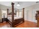 Bedroom with four-poster bed, wood floors, bright windows, and a nightstand at 3813 Blue Dasher Dr, Kissimmee, FL 34744