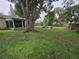 This is a spacious backyard featuring a large tree, lush greenery, a shed, and decorative garden elements at 4123 Gander Ave, Orlando, FL 32822