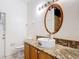 Bathroom features a round vessel sink on granite countertop and a decorative wood-framed mirror at 451 Acacia Tree Way, Kissimmee, FL 34758