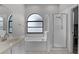 Well-lit bathroom showcasing a soaking tub, glass-enclosed shower, and decorative arched window at 545 Hardwood Cir, Orlando, FL 32828