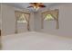 Comfortable bedroom with a ceiling fan and two windows with decorative curtains at 5812 Viking Rd, Orlando, FL 32808