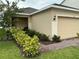 Charming single-Gathering home with a beige exterior, attached garage, manicured landscaping and brick walkway at 6841 Wilson Hammock Ave, Groveland, FL 34736