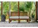 Inviting outdoor seating area with a wooden bench, soft cushions, and lush tropical plants at 725 S Hampton Ave, Orlando, FL 32803