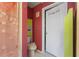 A view of a toilet, a door and a decorative curtain in a red colored bathroom at 730 Siena Palm Dr # 201, Celebration, FL 34747