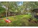 Serene backyard oasis with mature trees, a wooden fence, and a custom cornhole game for recreation at 7806 Compass Dr, Orlando, FL 32810