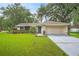 Well-maintained single-story home with a lush green lawn and mature trees in a quiet neighborhood at 7806 Compass Dr, Orlando, FL 32810