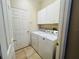 Bright laundry room equipped with a washer, dryer, and white storage cabinets at 830 Moonlit Ln, Casselberry, FL 32707
