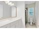 Bright bathroom with white cabinetry, light countertops, a large mirror and glass enclosed shower at 8480 Adalina Pl, Orlando, FL 32827