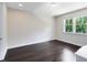 A spacious bedroom with dark hardwood floors, neutral walls, and natural light from the large windows at 8480 Adalina Pl, Orlando, FL 32827