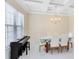 Elegant dining room with a chandelier, coffered ceiling, piano and a large window providing natural light at 8480 Adalina Pl, Orlando, FL 32827