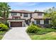 Elegant two-story home featuring a red tile roof, lush landscaping, and a paved driveway leading to a two-car garage at 8480 Adalina Pl, Orlando, FL 32827
