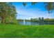 Scenic pond with a water fountain surrounded by lush green grass and mature trees at 8480 Adalina Pl, Orlando, FL 32827