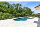 Beautiful pool, surrounded by travertine pavers and lush landscaping, offering a private backyard oasis at 8480 Adalina Pl, Orlando, FL 32827