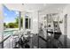 Modern dining area with glass table, chairs, black tile floors, grand staircase, and pool view at 9138 Great Heron Cir, Orlando, FL 32836