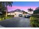 Stunning home exterior featuring a paver driveway, lush landscaping, and luxury cars at dusk at 9138 Great Heron Cir, Orlando, FL 32836