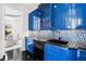 Galley kitchen showcasing blue cabinets, stainless steel appliances and mosaic tiling at 9138 Great Heron Cir, Orlando, FL 32836