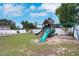 Large backyard featuring a playground, lush green grass, a white fence, and mature trees at 1167 Lake Blanche Dr, Orlando, FL 32808