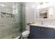Modern bathroom with glass shower, gray tile, blue vanity, and decorative mirror at 1167 Lake Blanche Dr, Orlando, FL 32808
