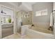 Bright bathroom with a glass enclosed shower, soaking tub, and a view into the main bedroom at 14016 Fox Glove St, Winter Garden, FL 34787