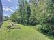 Serene backyard featuring green grass, mature trees, and two chaise lounges for relaxation at 14044 Chicora Crossing Blvd, Orlando, FL 32828