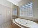 Close-up of soaking tub with glass block window and tiled shower in bathroom at 14044 Chicora Crossing Blvd, Orlando, FL 32828