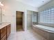 Bright bathroom with large soaking tub, walk-in closet, and glass block window at 14044 Chicora Crossing Blvd, Orlando, FL 32828
