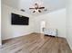 Large bedroom with modern gray wood floors, a ceiling fan, and a television mounted on the wall at 14044 Chicora Crossing Blvd, Orlando, FL 32828