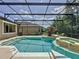 View of a screened-in pool and spa with surrounding trees at 14044 Chicora Crossing Blvd, Orlando, FL 32828
