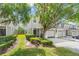 Exterior view of townhome with a well-manicured lawn, green shrubbery and a two-car garage at 14213 Turning Leaf Dr, Orlando, FL 32828