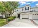 Exterior view of two story townhome featuring two-car garage, dark shutters, and green shrubbery at 14213 Turning Leaf Dr, Orlando, FL 32828