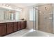 Modern bathroom features dual sinks, a large mirror, and a glass shower enclosure at 15477 Blackbead St, Winter Garden, FL 34787