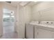A bright laundry room with a washer and dryer, with shelves for storage of materials at 15477 Blackbead St, Winter Garden, FL 34787
