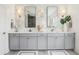 Modern bathroom with dual sinks, gray cabinetry, large mirrors, and stylish tile backsplash at 15779 Tangerine Dream Ct, Winter Garden, FL 34787