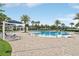 Resort-style community pool with palm trees, lounge chairs, and shaded seating areas for relaxation and recreation at 15779 Tangerine Dream Ct, Winter Garden, FL 34787