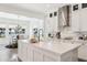 Elegant kitchen with marble backsplash, stainless steel vent hood, and island with sink and white cabinets at 15779 Tangerine Dream Ct, Winter Garden, FL 34787