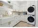 Well-appointed laundry room with white cabinets, gold hardware, and stacked washer and dryer at 15779 Tangerine Dream Ct, Winter Garden, FL 34787