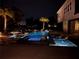 Nighttime view of the pool and spa area with lighting accents, palm trees and building facade at 15779 Tangerine Dream Ct, Winter Garden, FL 34787