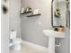 Modern powder room featuring a pedestal sink, decorative shelves, and stylish wall decor at 15779 Tangerine Dream Ct, Winter Garden, FL 34787