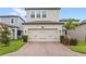 A two-car garage showing the driveway and the front of the home in a residential neighborhood with a landscaped lawn at 16013 Tollington Aly, Winter Garden, FL 34787
