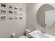 Stylish powder room featuring a round mirror, a white pedestal sink, and gallery wall with framed photos at 16013 Tollington Aly, Winter Garden, FL 34787