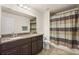 Bathroom with double sink vanity, large mirror, and a toilet with a shower and striped curtain at 1613 Water Elm Ct, Orlando, FL 32825