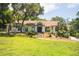 Charming single-story home with arched windows, landscaped yard, and mature trees at 16400 Lakeshore Dr, Minneola, FL 34715