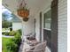Inviting front porch with decorative hanging plants, wicker chairs, and a brick facade at 207 Ramsbury Ct, Longwood, FL 32779