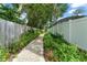 A planted and mulched side yard features a concrete walkway and privacy fencing at 207 Ramsbury Ct, Longwood, FL 32779