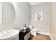 Well-lit powder room with a stylish sink, a round mirror, and elegant wall decor at 2267 Mossy Vine Ave, St Cloud, FL 34771