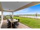 Covered outdoor patio with brick pavers, view of backyard and modern outdoor dining furniture at 2267 Mossy Vine Ave, St Cloud, FL 34771