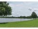Picturesque lakefront view with lush green grass and mature trees under a cloudy sky at 353 Wekiva Cove Rd, Longwood, FL 32779