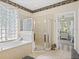 Bright bathroom featuring a tub, glass-enclosed shower, and classic decorative accents at 407 Grand Reserve Dr, Davenport, FL 33837